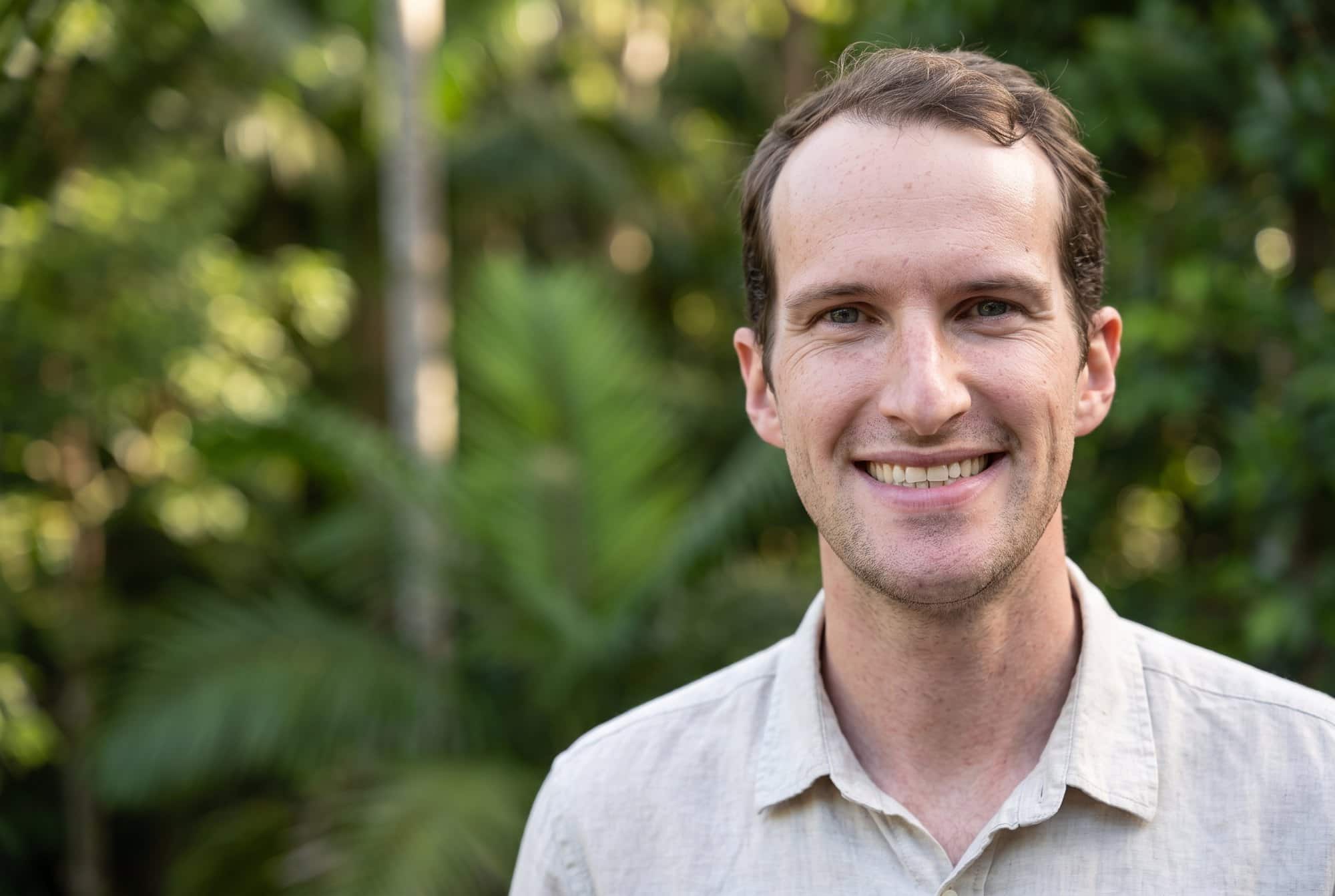 Peter Low smiling in a green rainforest garden